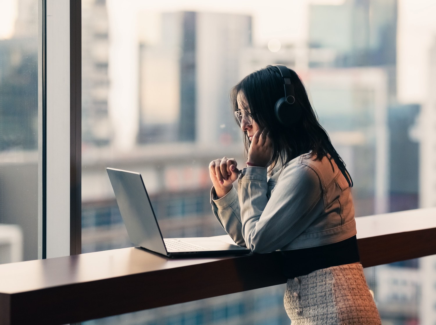 Person studying remotely on a laptop by a city window